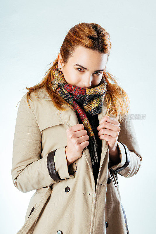 可爱的微笑的女孩在冬天的时尚大衣和围巾
