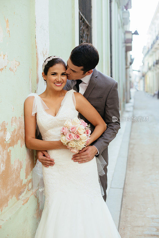 一对新婚夫妇在古巴哈瓦那的街道上接吻