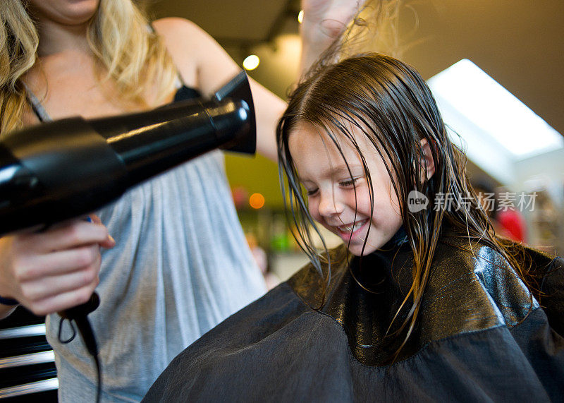 一个女孩在沙龙里用吹风机做头发