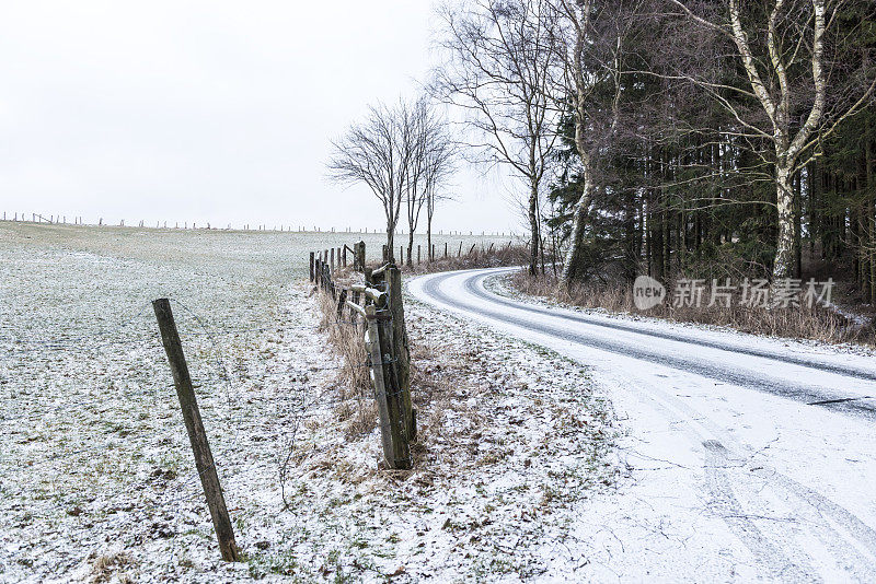 积雪覆盖了泥泞的道路，留下了车轮的痕迹