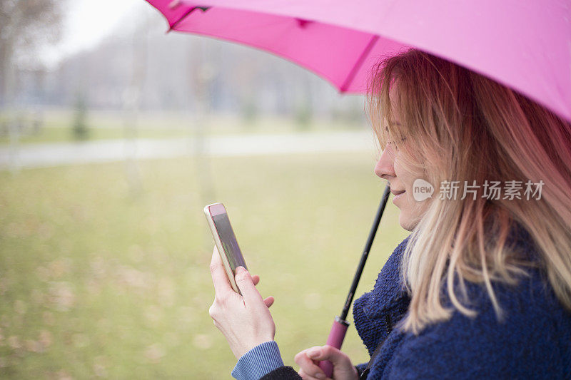 年轻女子与手机在雨天