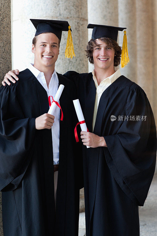 两名毕业生面带微笑，手拿毕业证