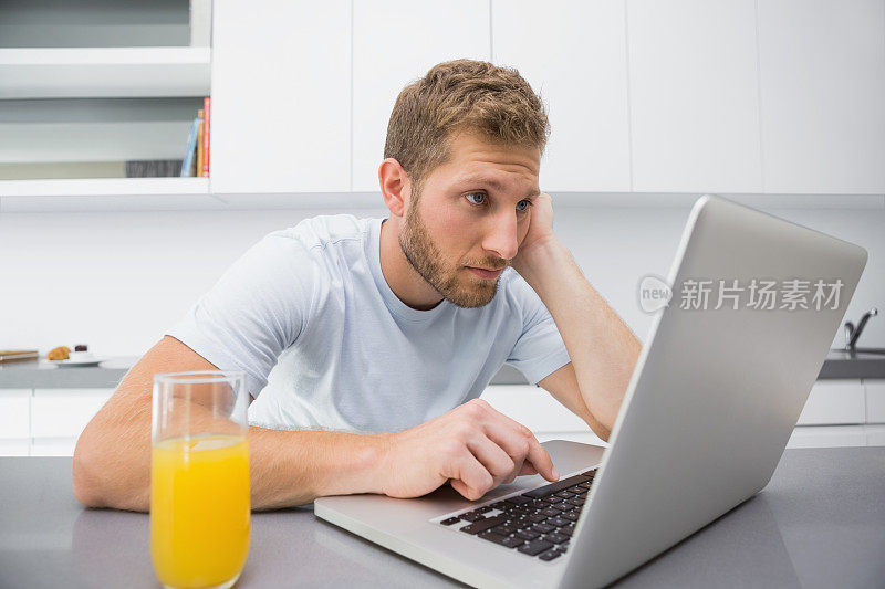 吃早餐时用笔记本电脑的男人