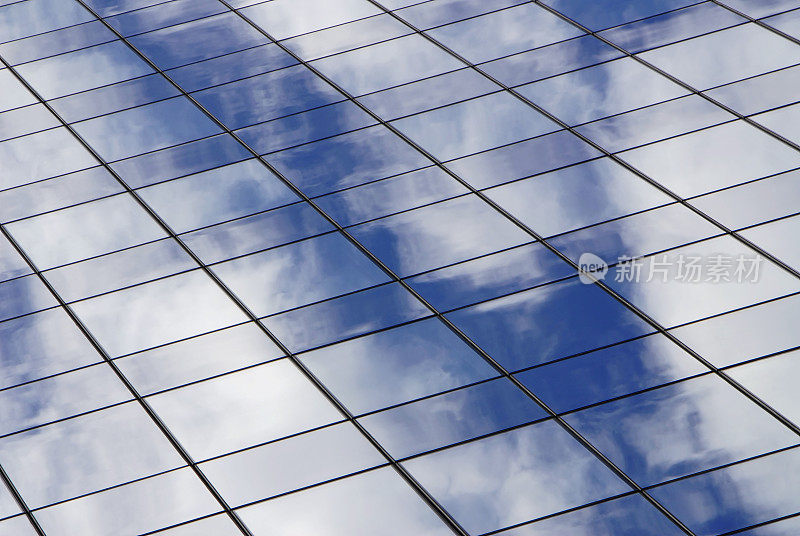 玻璃的办公室窗户反映了蓝天和白云