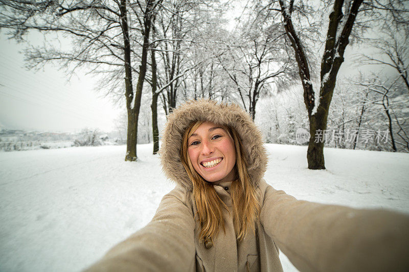 快乐的女人在公园里与雪自拍