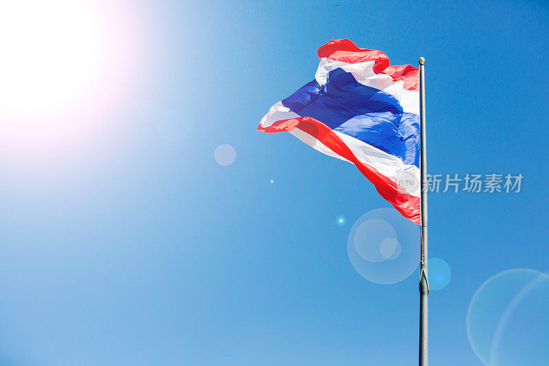 挥舞着以蓝天为背景的泰国国旗。
