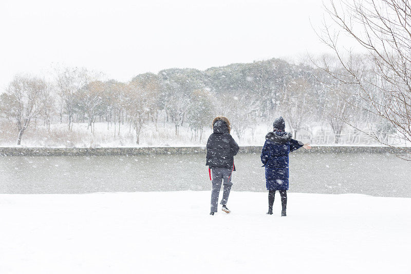 女性朋友穿着暖和的衣服在雪地里欢呼
