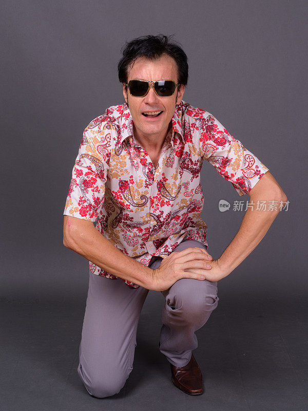 成熟英俊的游客男子穿着夏威夷衬衫准备在灰色背景下度假