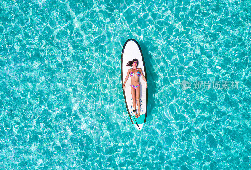 穿着比基尼的女人正在冲浪板上晒太阳