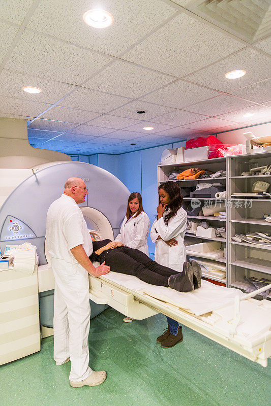 女性患者进行MRI扫描....，助理放射科主任和两名医生