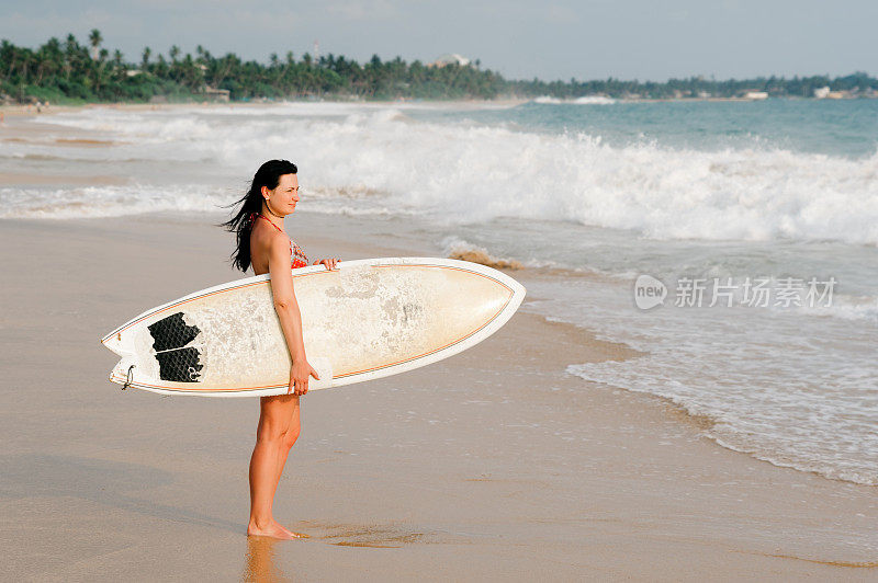 年轻的女士和冲浪板在热带沙滩上散步。斯里兰卡。弥留。
