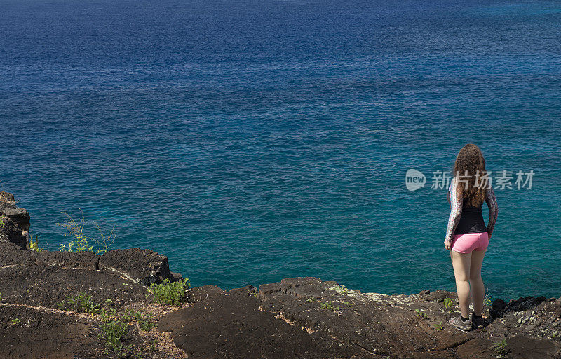 旅行中的美国女人沿着夏威夷海边的悬崖行走