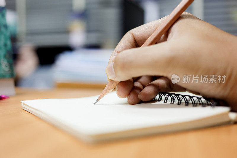 男人用铅笔在纸上写便条。