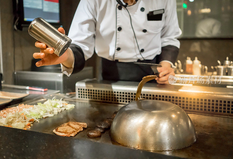 厨师在顾客面前将盐放入热锅中。日本Tepanyaki牛排