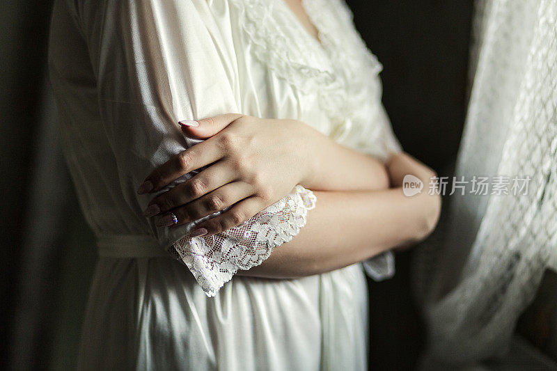 新娘穿着睡袍靠近窗户，女人在婚礼前准备