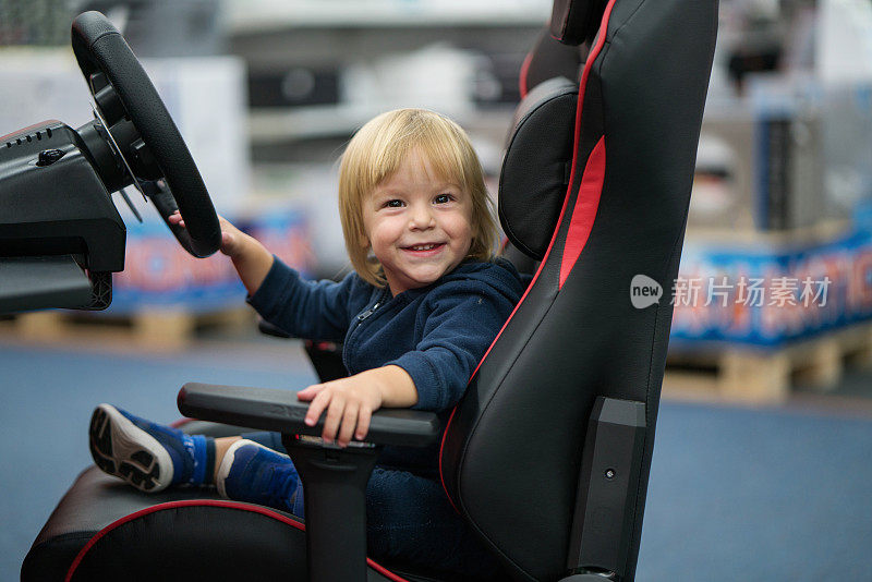 可爱的孩子有乐趣，而坐在赛车模拟器座位。