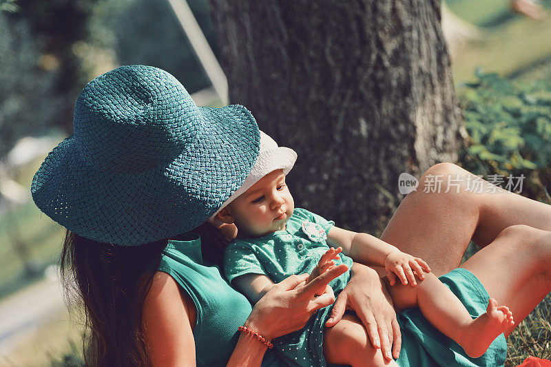 快乐的母亲和孩子的女儿坐在一起在夏天的一天
