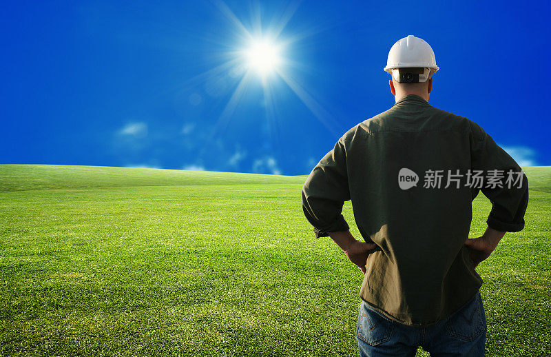 男建筑工人在绿草如茵的风景在阳光灿烂的天空