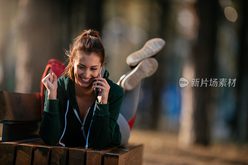 漂亮的年轻运动女性与智能手机在户外