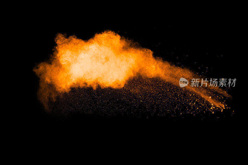 橙色尘埃粒子在黑色背景上爆炸。彩色粉末粉尘飞溅。