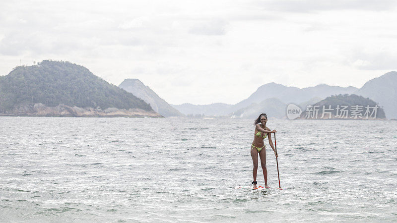 在海上用桨操纵桨板的年轻女子