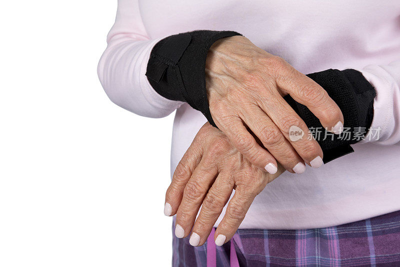 老年妇女戴着腕管综合征支架抓手腕疼痛