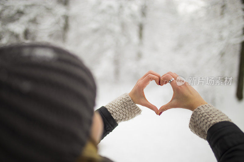 女人在冬天双手制作心形的象征