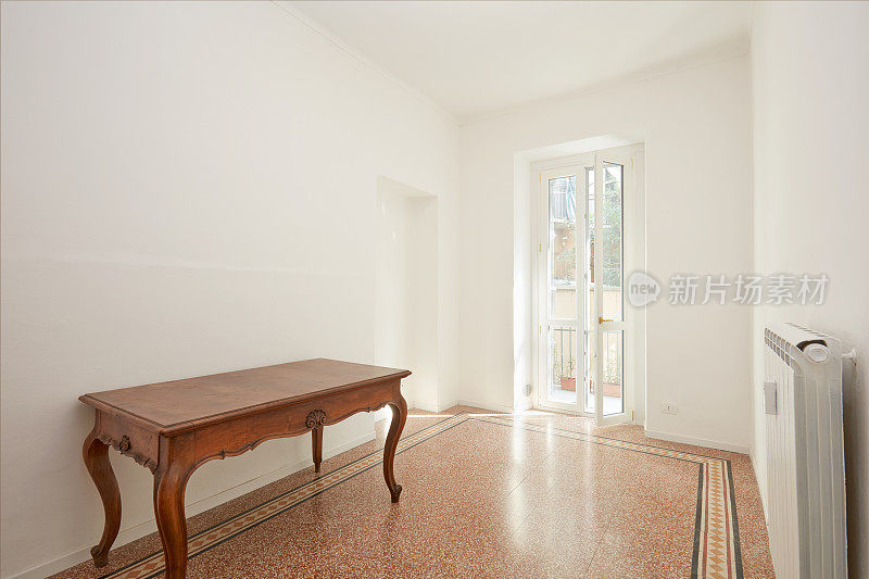 在阳光明媚的日子里，白色的房间和木桌在装修过的公寓