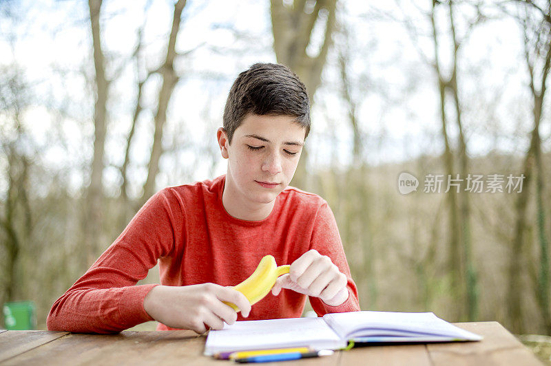 一个在城市公园里学习的少年。吃健康零食的时间到了