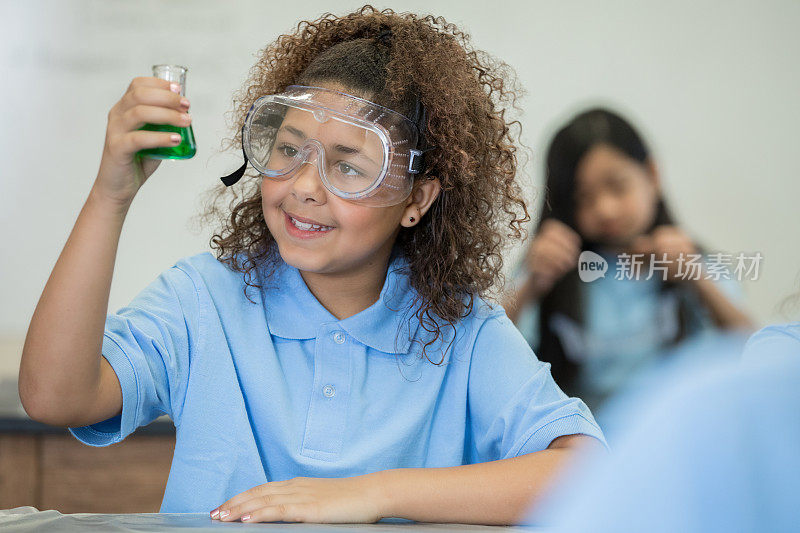可爱的小学年龄的混血小女孩做化学实验在学校的科学实验室