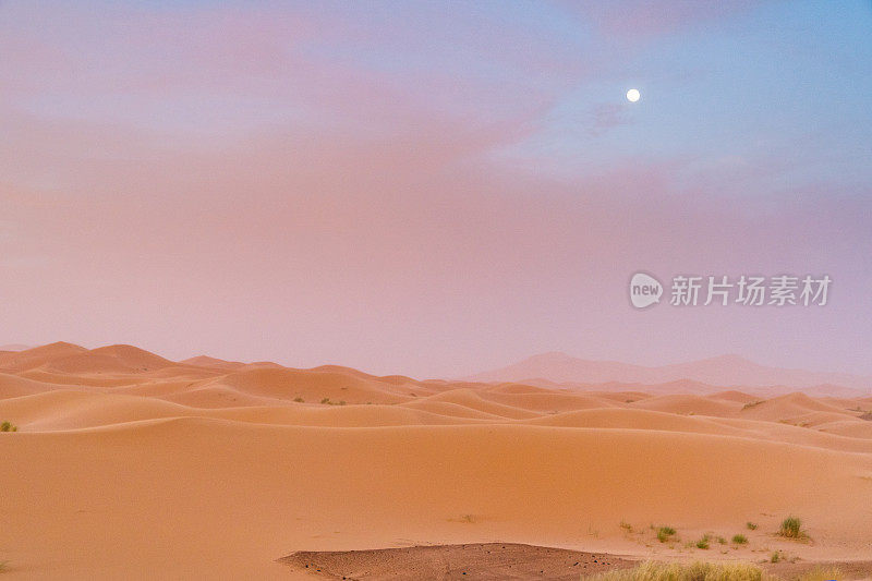 撒哈拉沙漠的夜晚。巨大的橙色沙色沙丘和多云的天空在Merzouga沙漠，摩洛哥。