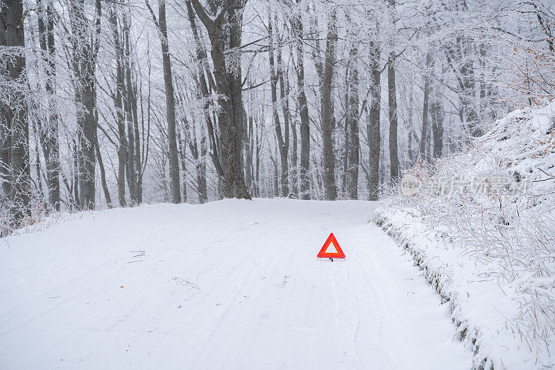 在积雪的山路上发生交通事故。三角代表交通事故。路标。