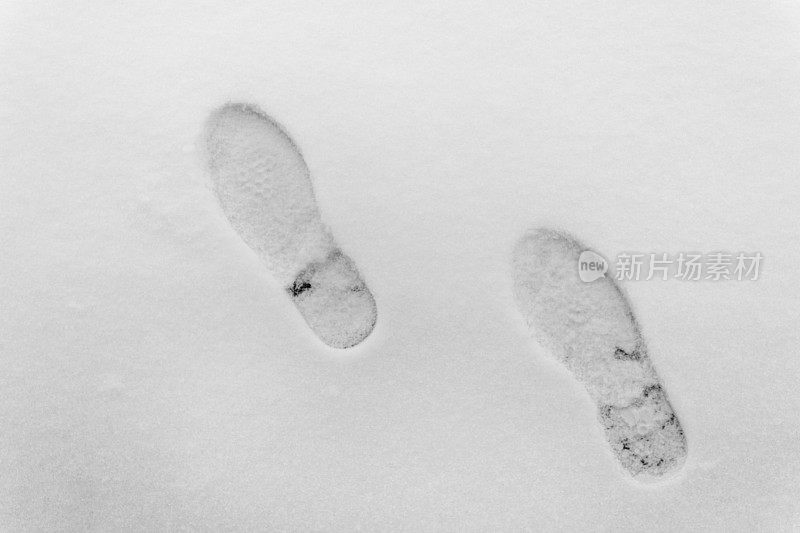 洁白的雪地上清晰的脚印。顶视图。雪表面的纹理。雪地里有人类的脚印。冬季自然背景。雪地里的鞋印——在雪地里行走是危险的