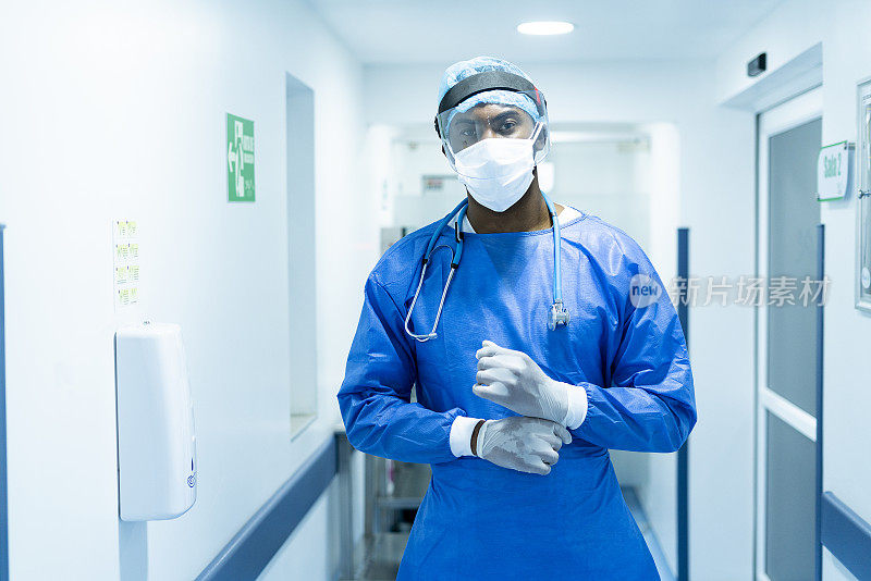 在ICU医院，医生交叉双臂看着镜头，穿着生物安全服