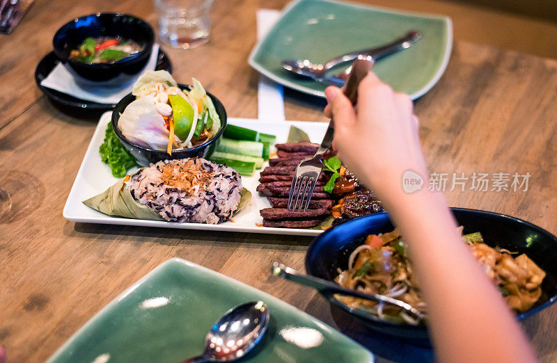 女吃泰国烤肉鸡和牛肉服务在盘子里的泰国餐