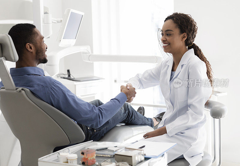 友好的非洲女牙医与男病人握手