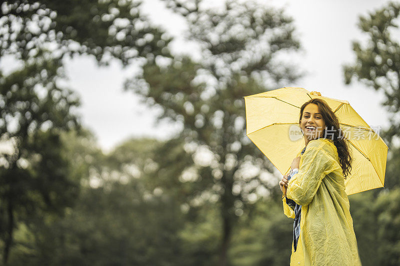 快乐的女人微笑着行走在雨天