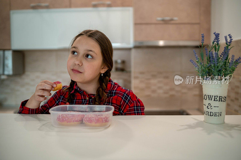 对孩子的饮食。悲伤和不快乐的孩子触及甜甜圈。孩子们的美味食物。孩子在看甜甜圈。垃圾食品上瘾。