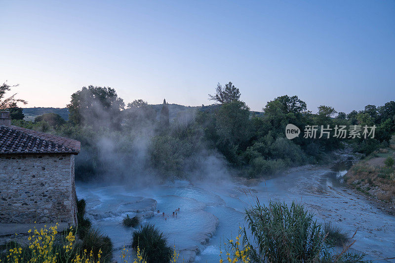 在意大利托斯卡纳的萨图尼亚，四个年轻人正在用瀑布和温泉的天然温泉洗澡