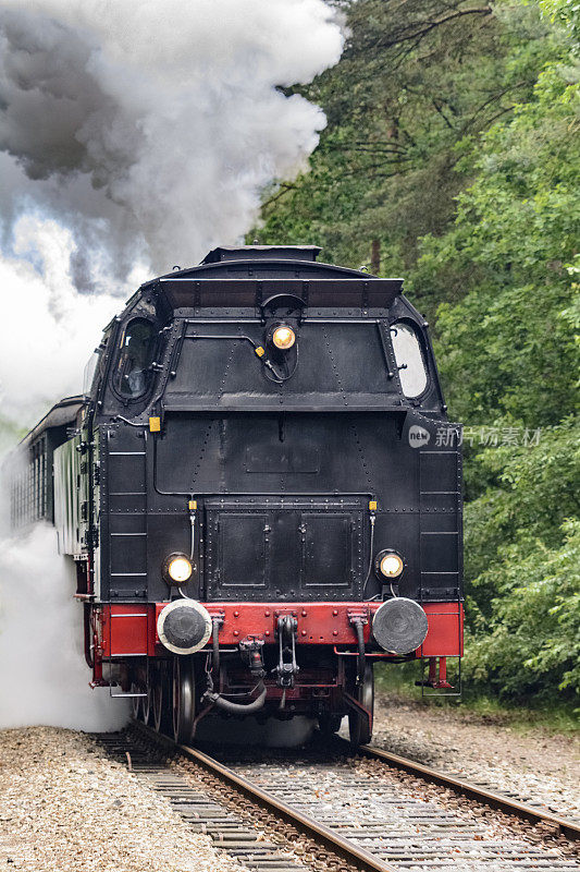 老式蒸汽火车拖着火车车厢在乡村景色中行驶