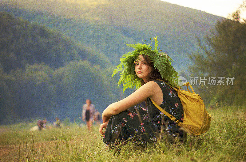 戴着蕨花环的女人坐在山上的草地上