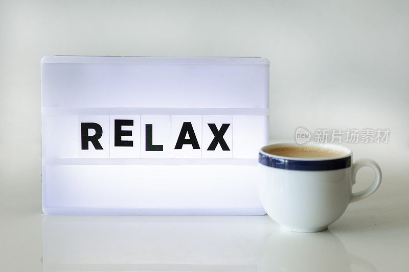 放松概念与文字灯箱和一杯咖啡在家庭办公室。