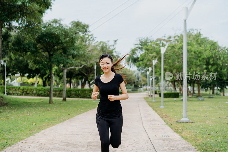 快乐的年轻亚洲女人在早上在公园跑步