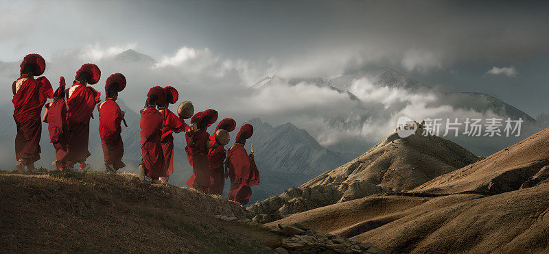 在尼泊尔的穆斯坦王国，年轻的僧侣们穿着传统的衣服，在群山的背景下走向一座古老的寺庙。