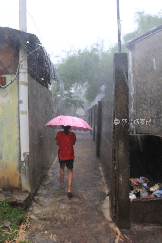 一个小女孩在倾盆大雨中带着雨伞。