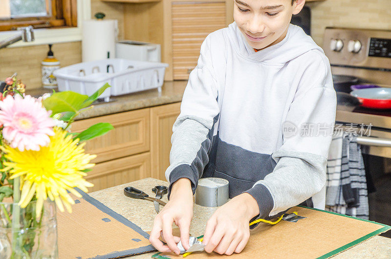 男孩用胶带把绳子粘在纸板上