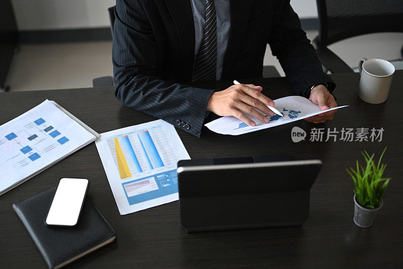 年轻成功的商人在现代办公室里用平板电脑分析财务文件和广告。