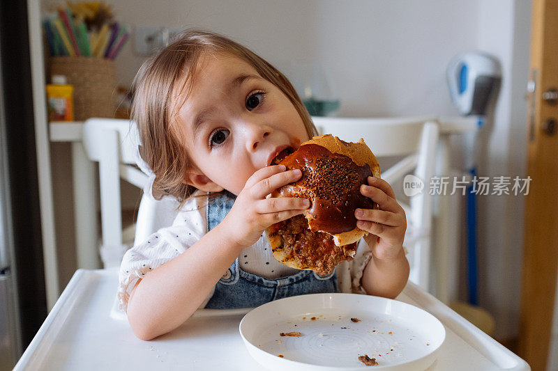 小女孩在厨房里吃汉堡包