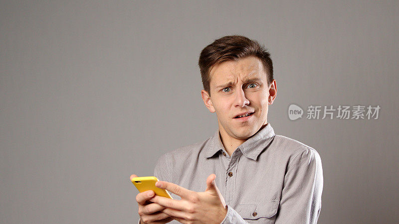 一名白人男子看着手机，脸上带着惊讶的表情