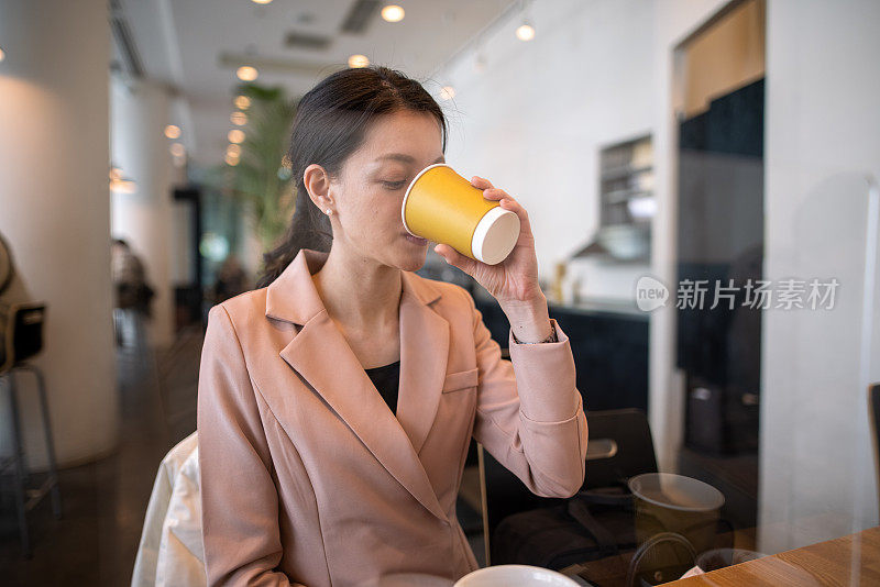 年轻的女商人午餐后在咖啡馆喝咖啡